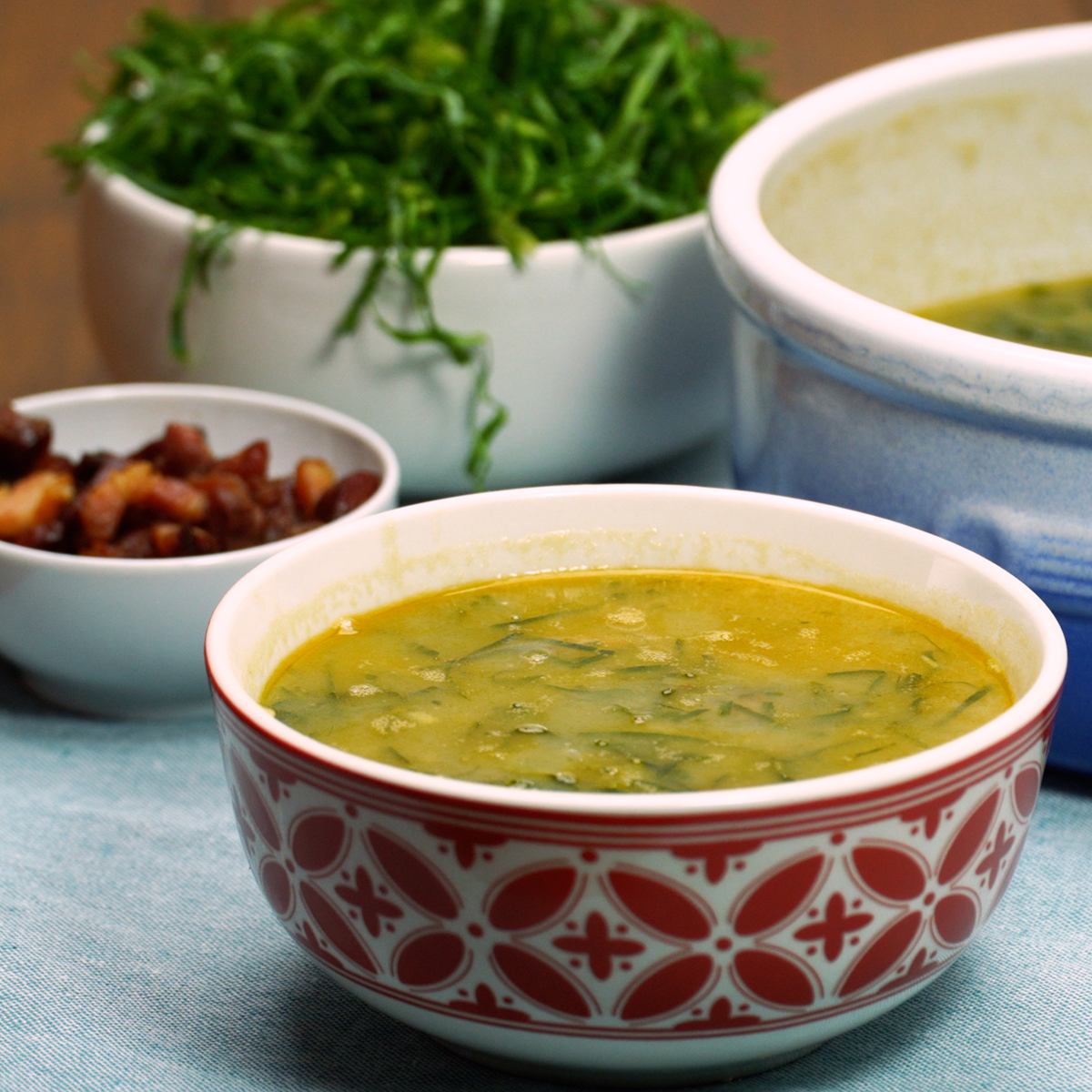 Bowl of Caldo Verde finished with olive oil and smoked sausage slices.