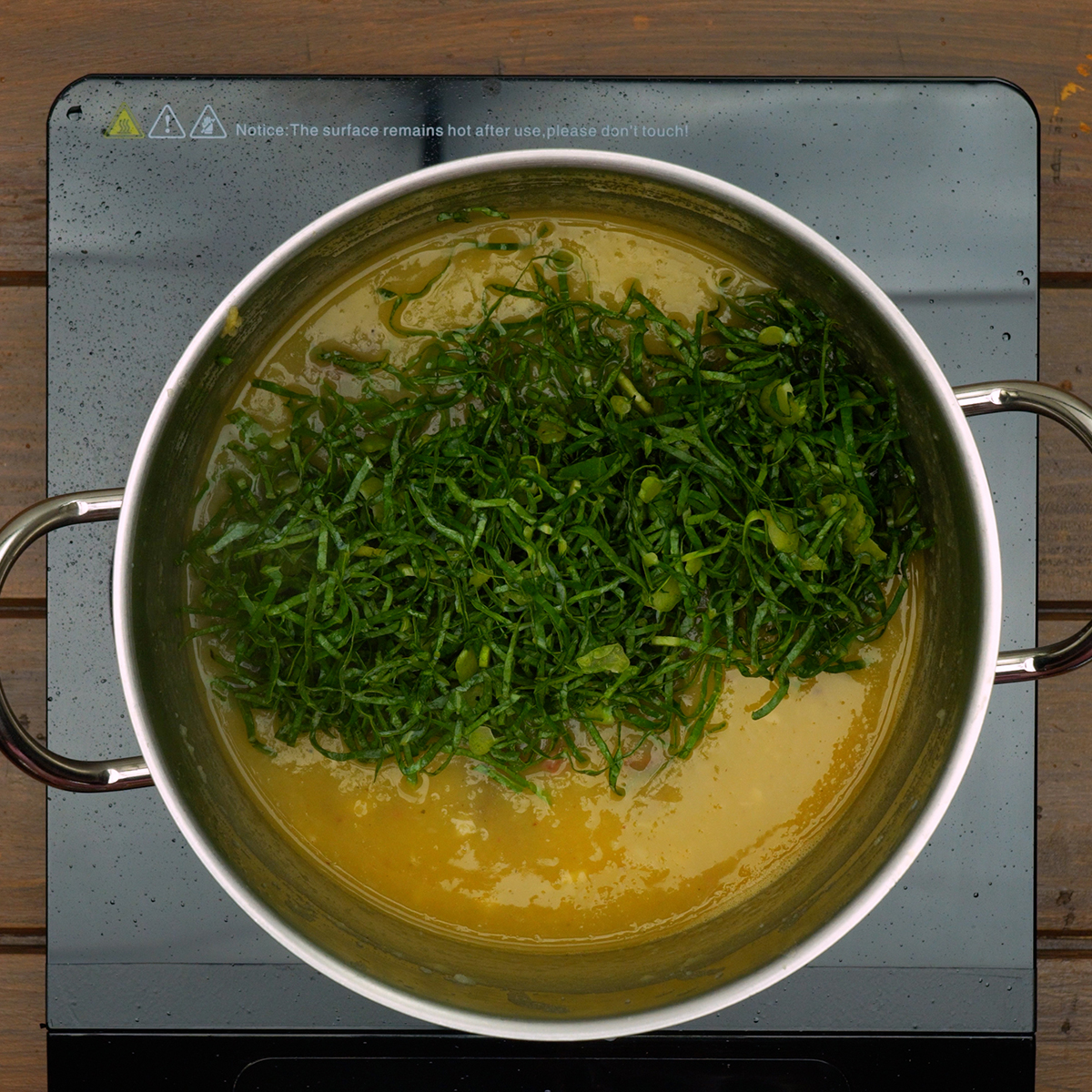 Shredded kale being stirred into Caldo Verde soup.