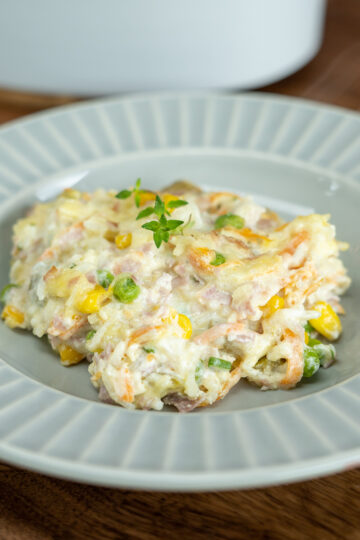 Plated baked creamy rice with ham and thyme as a garnish.