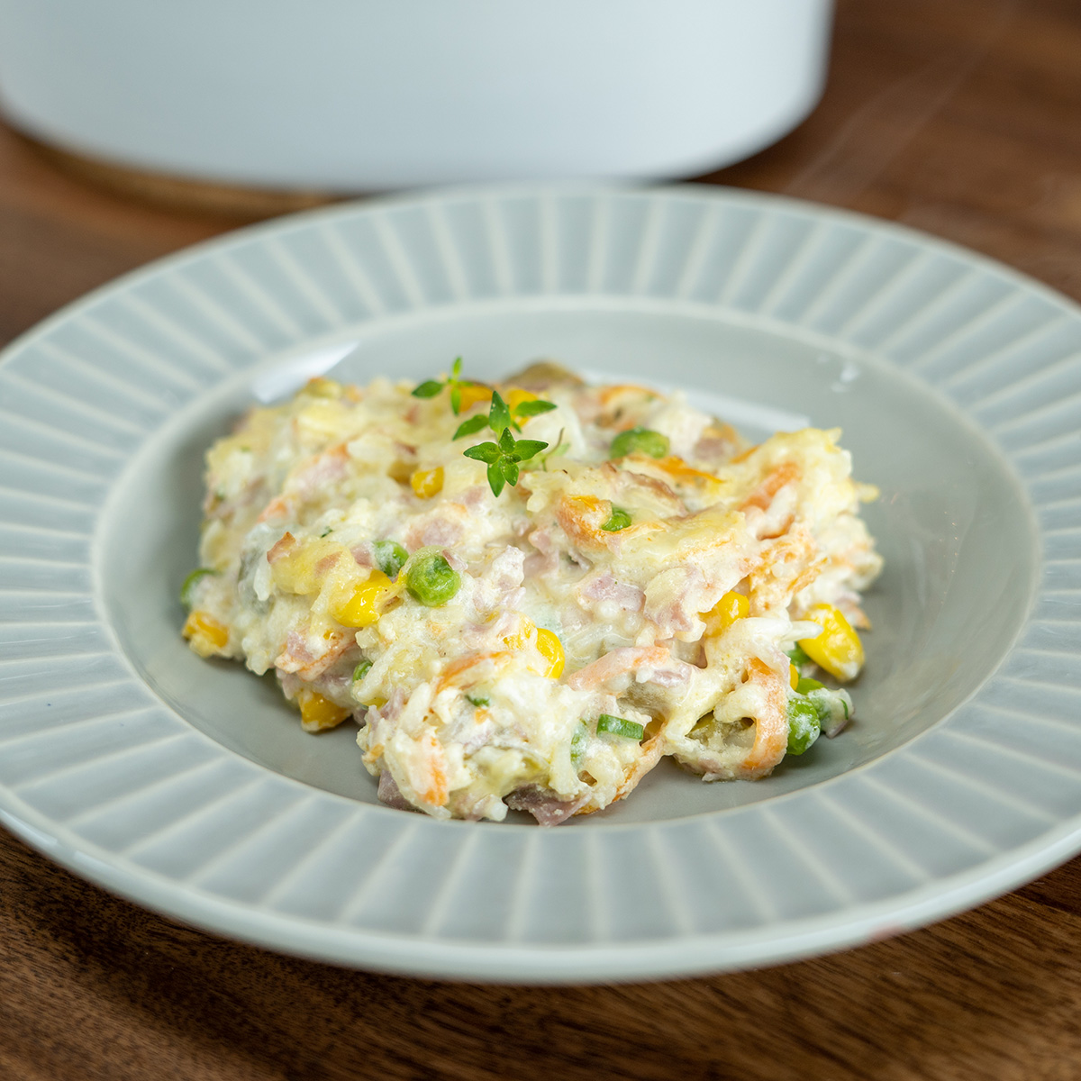 Plated baked creamy rice with ham and thyme as a garnish.