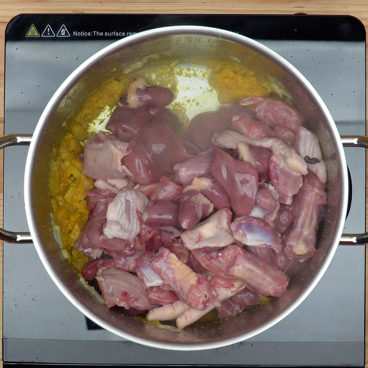 Miúdos de frango sendo misturados no refogado com temperos.