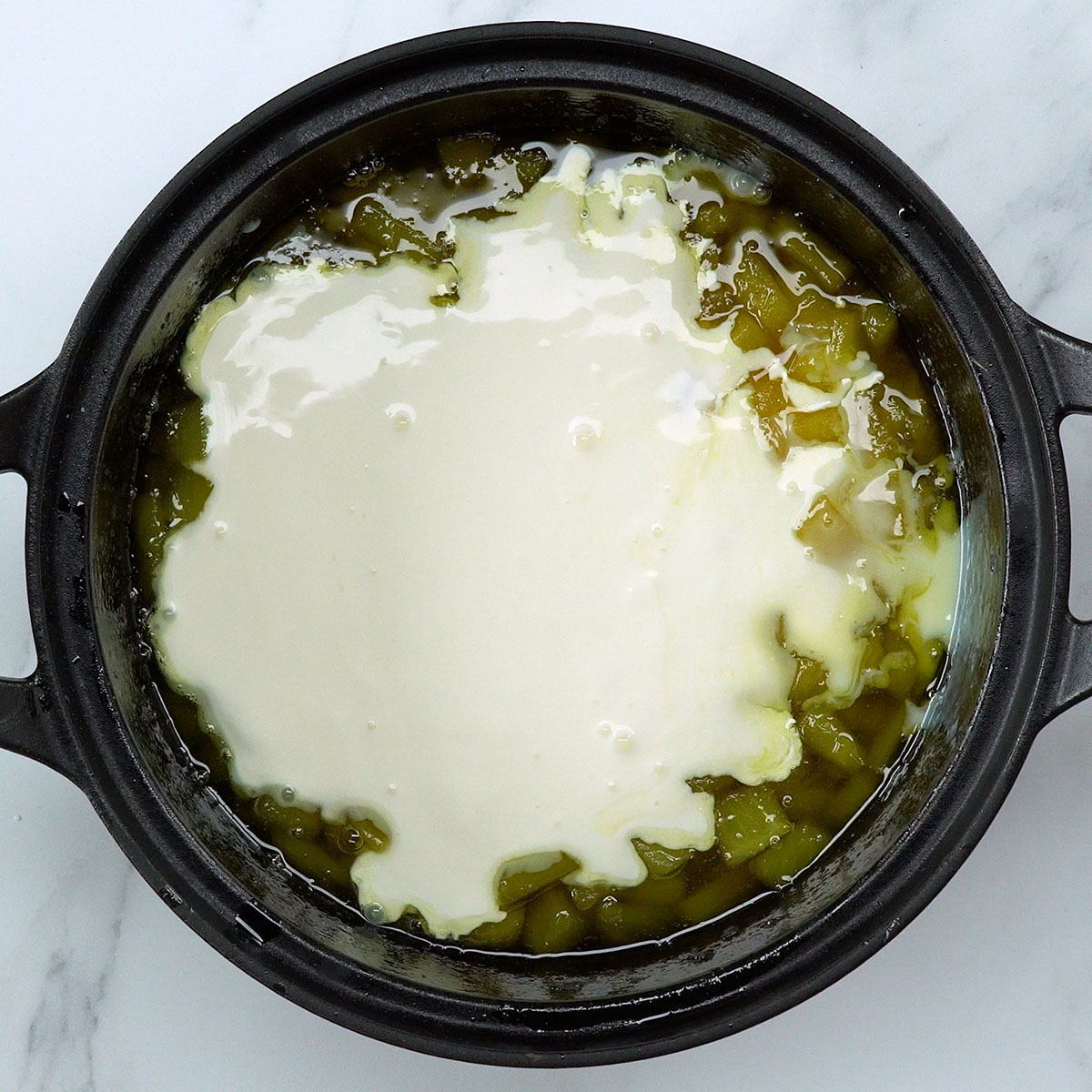 Sweetened condensed milk and cream being added to the pineapple mixture.
