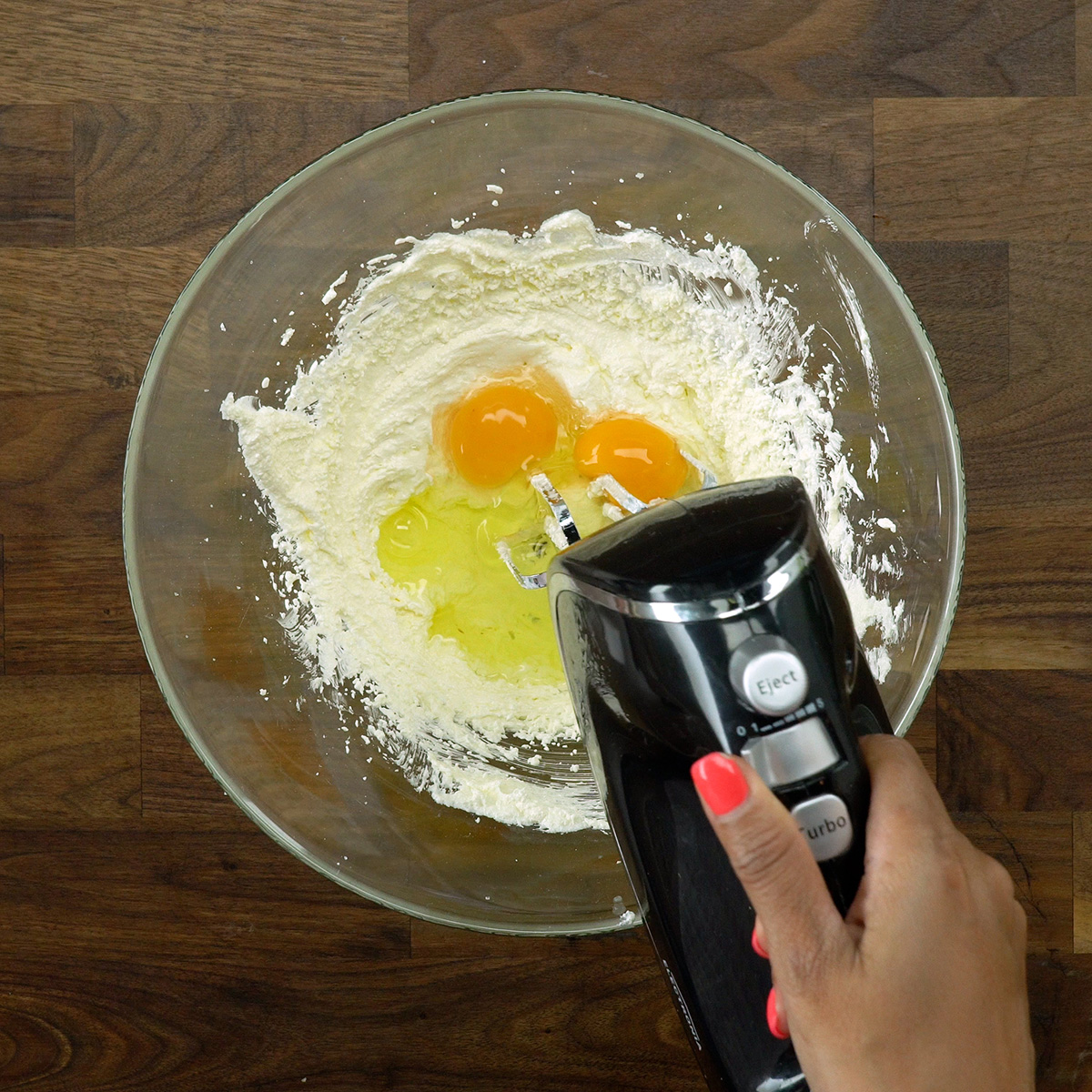 Eggs being added to apple cinnamon cake batter.