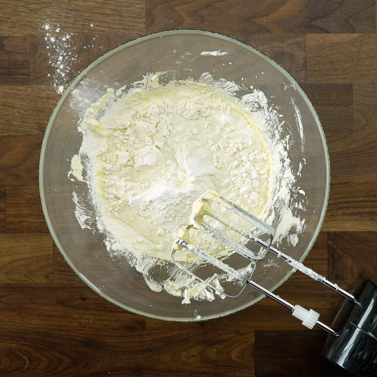 Flour, baking powder, and milk being added to apple cake batter.