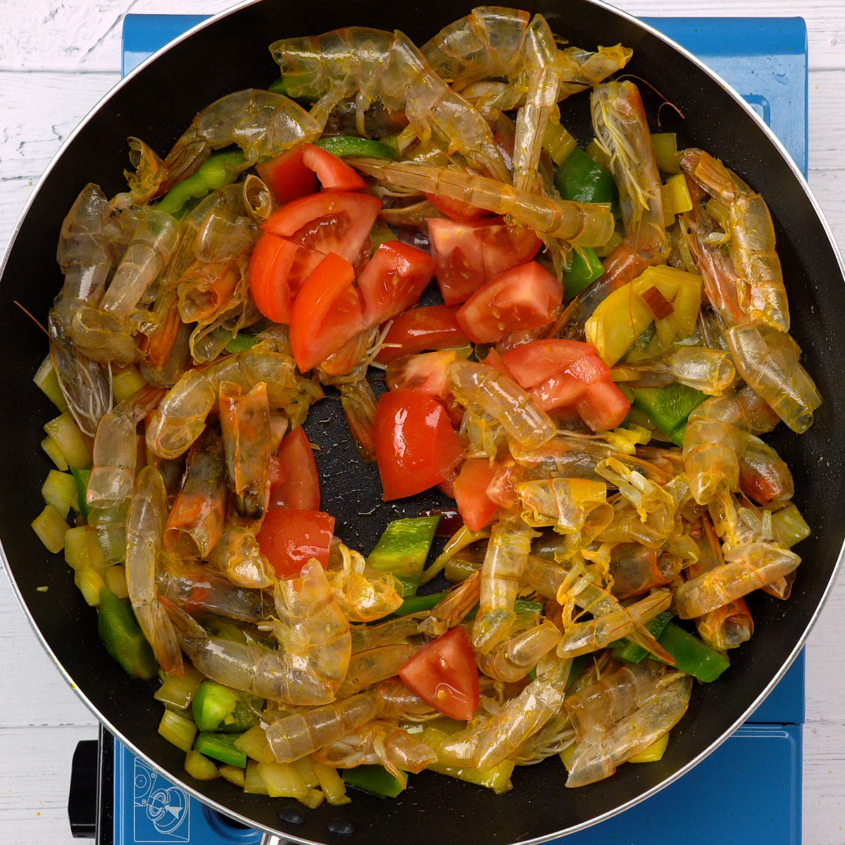 Tomato being added to the shrimp shell sauce base.