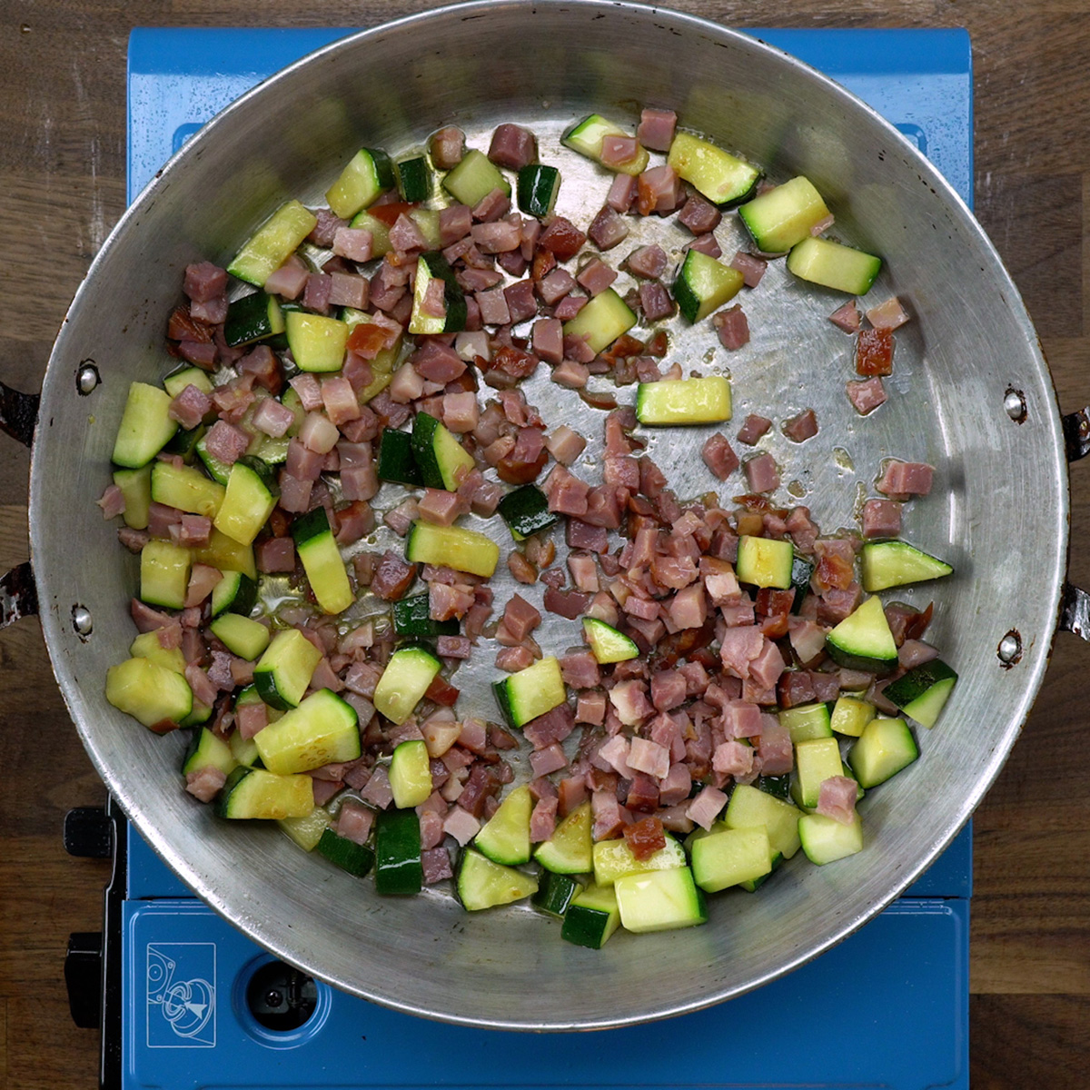 Diced bacon browning in a skillet.