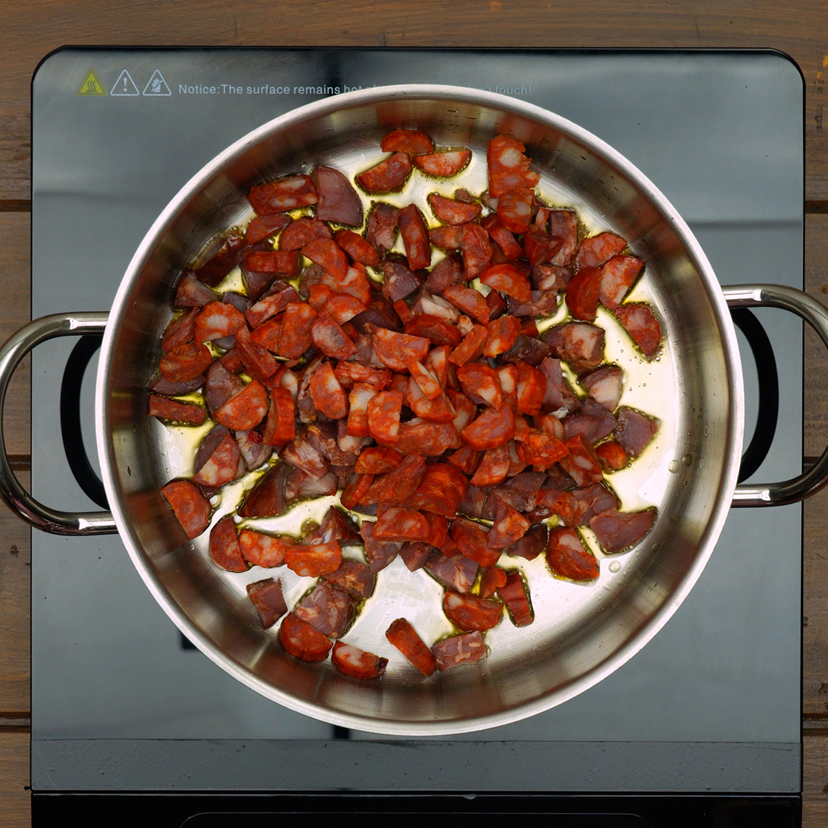 Bacon, chorizo, and sausage cooking in olive oil for smoky flavor.