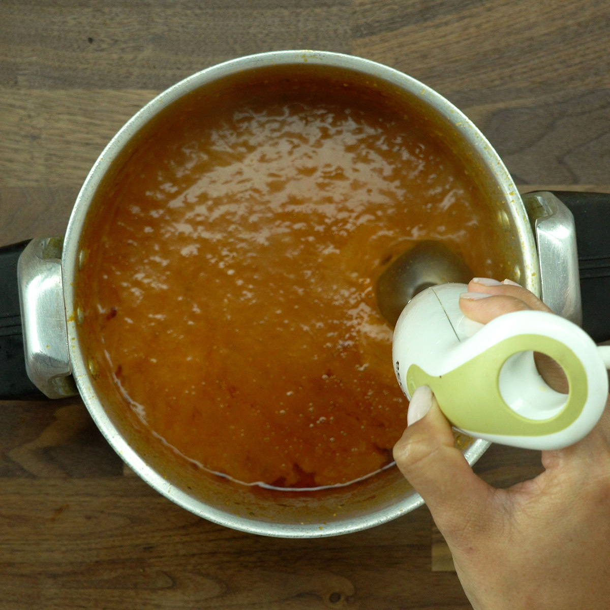Eye of round roast sauce being blended with an immersion blender until smooth.