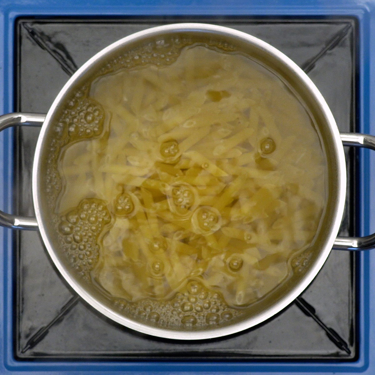 Penne pasta boiling in a pot of salted water.