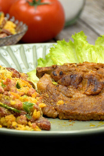 Brazilian farofa with bacon and sausage served with meat and lettuce.