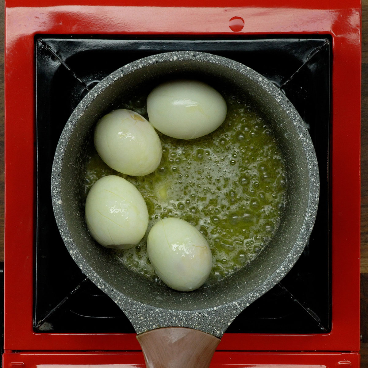 Hard-boiled eggs browning lightly in a skillet.