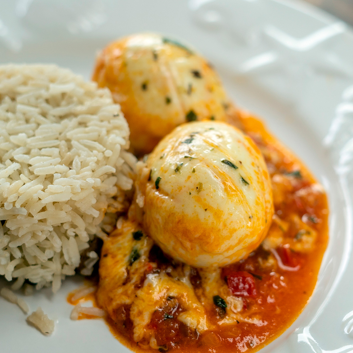 Cheesy eggs in tomato sauce plated with rice.
