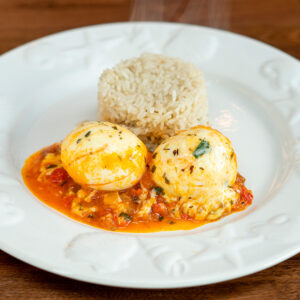 Plate of cheesy eggs in tomato sauce served with white rice.