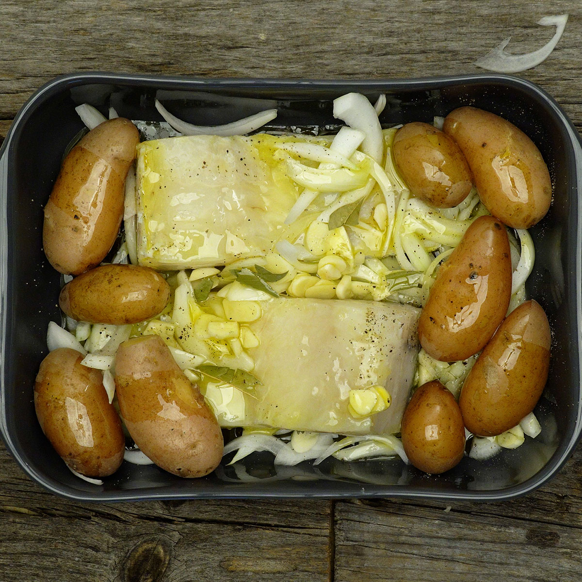Cod and potatoes seasoned with olive oil, garlic and onion before baking