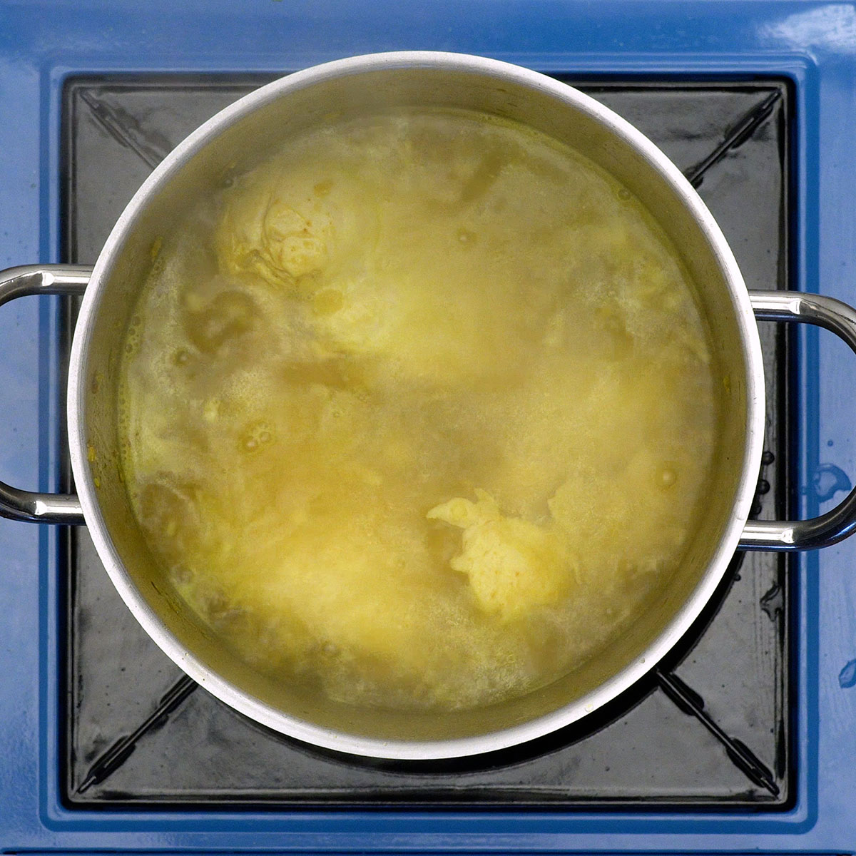 Chicken breast cooking in a pot with seasonings.