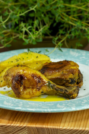 Plated creamy mustard mayo baked chicken thighs and drumsticks with potatoes and parsley.
