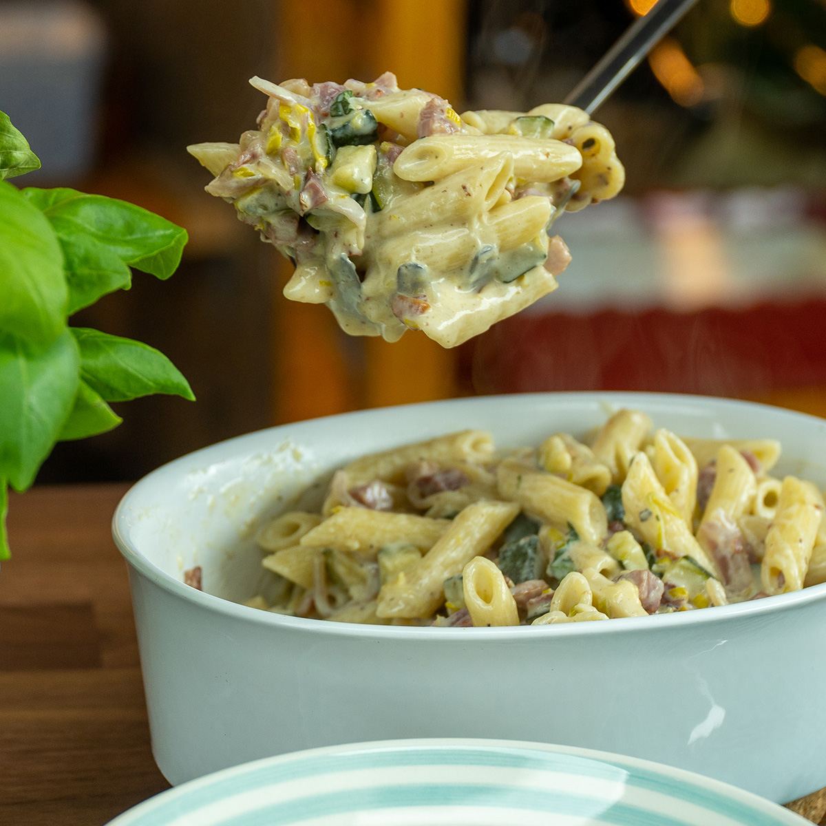 Penne with zucchini and bacon served on a plate.