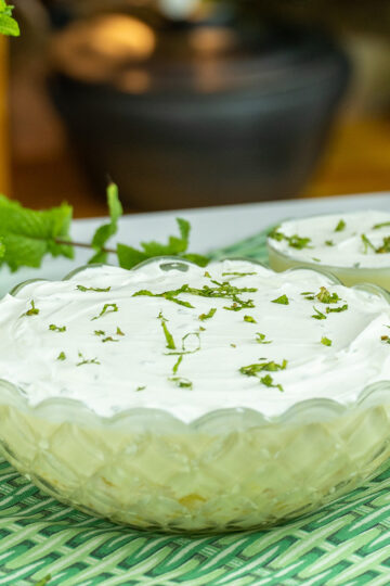 Creamy pineapple dessert topped with whipped cream and chopped mint.