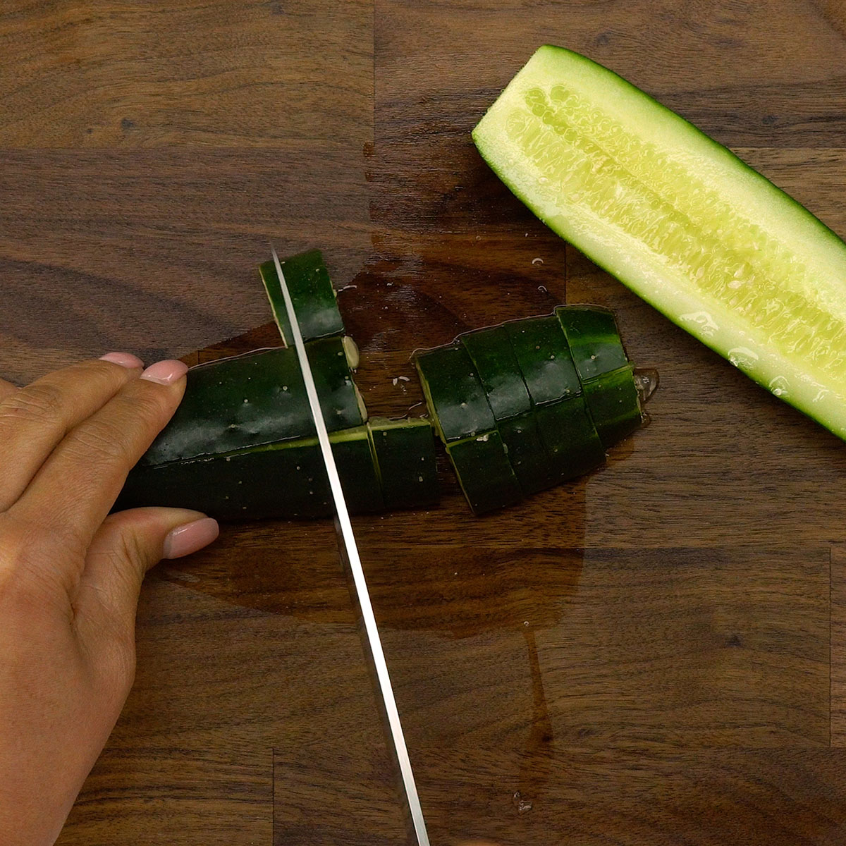 Fresh cucumber being diced into small pieces.