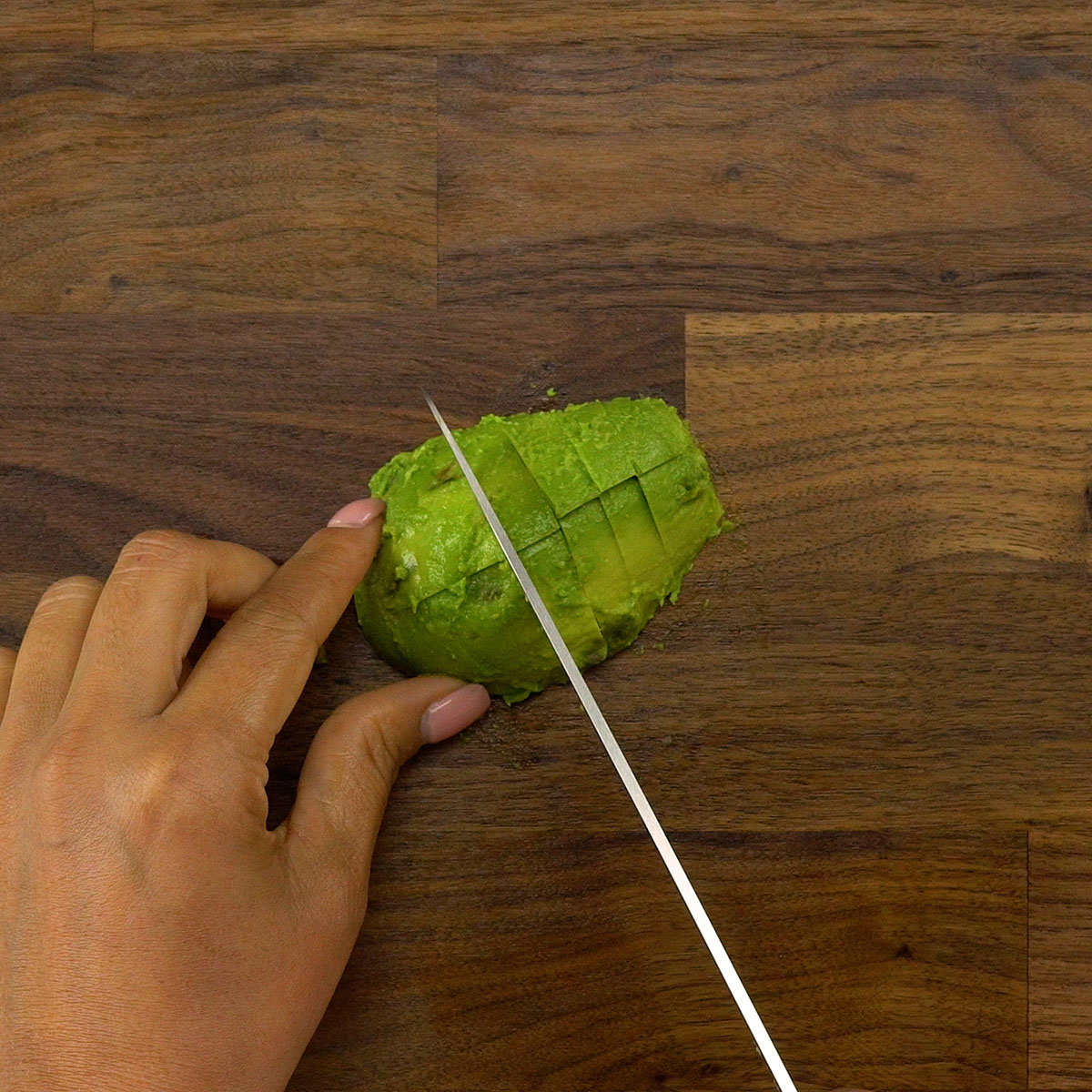 Ripe avocado being cut into cubes.