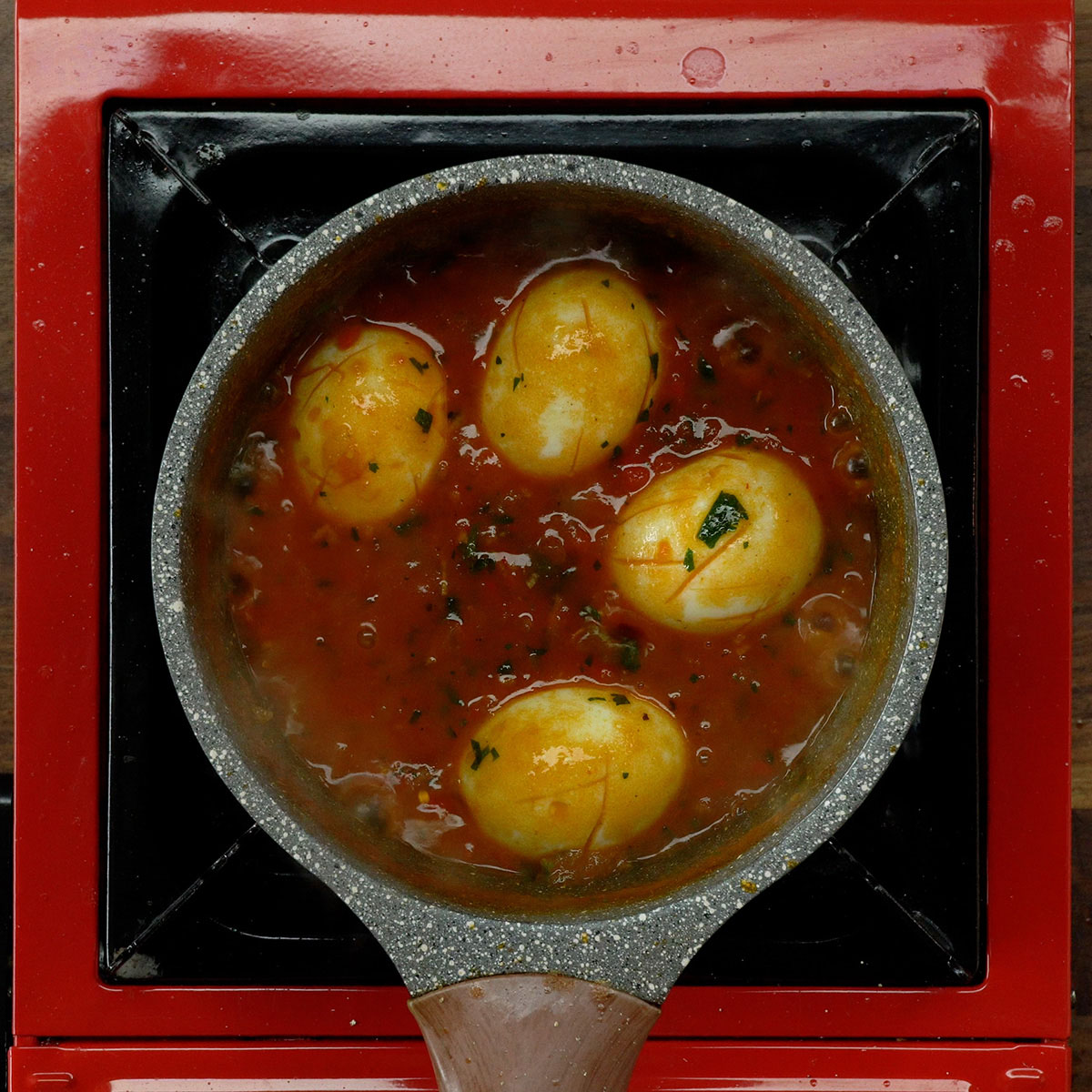 Hard-boiled eggs returned to the tomato sauce with parsley.