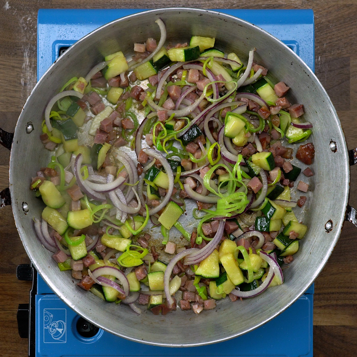 Leek, red onion and garlic being sautéed in a skillet.