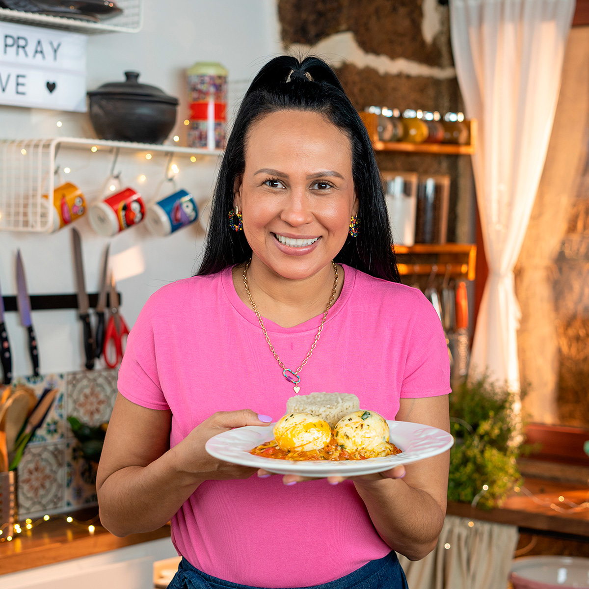 Mara Rodrigues holding a serving of cheesy eggs in tomato sauce.