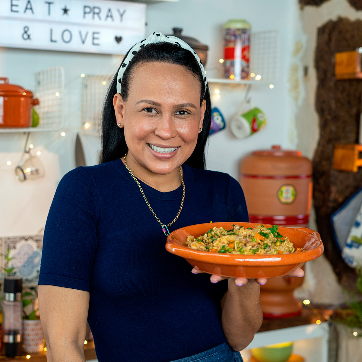 Mara Rodrigues holding a plate of chicken wings and rice.