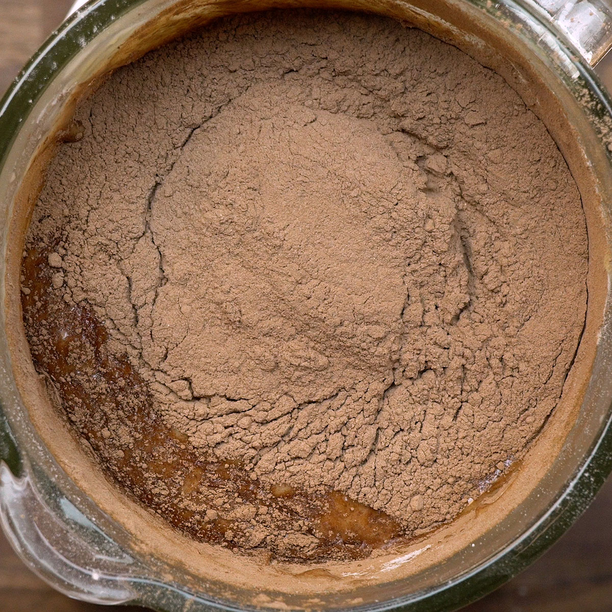 Cocoa powder being mixed into chocolate cake batter with a spoon.
