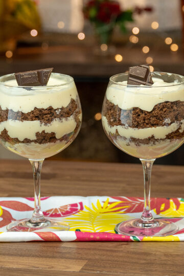 Passion fruit mousse cup layered with chocolate cake and decorated with chocolate pieces.