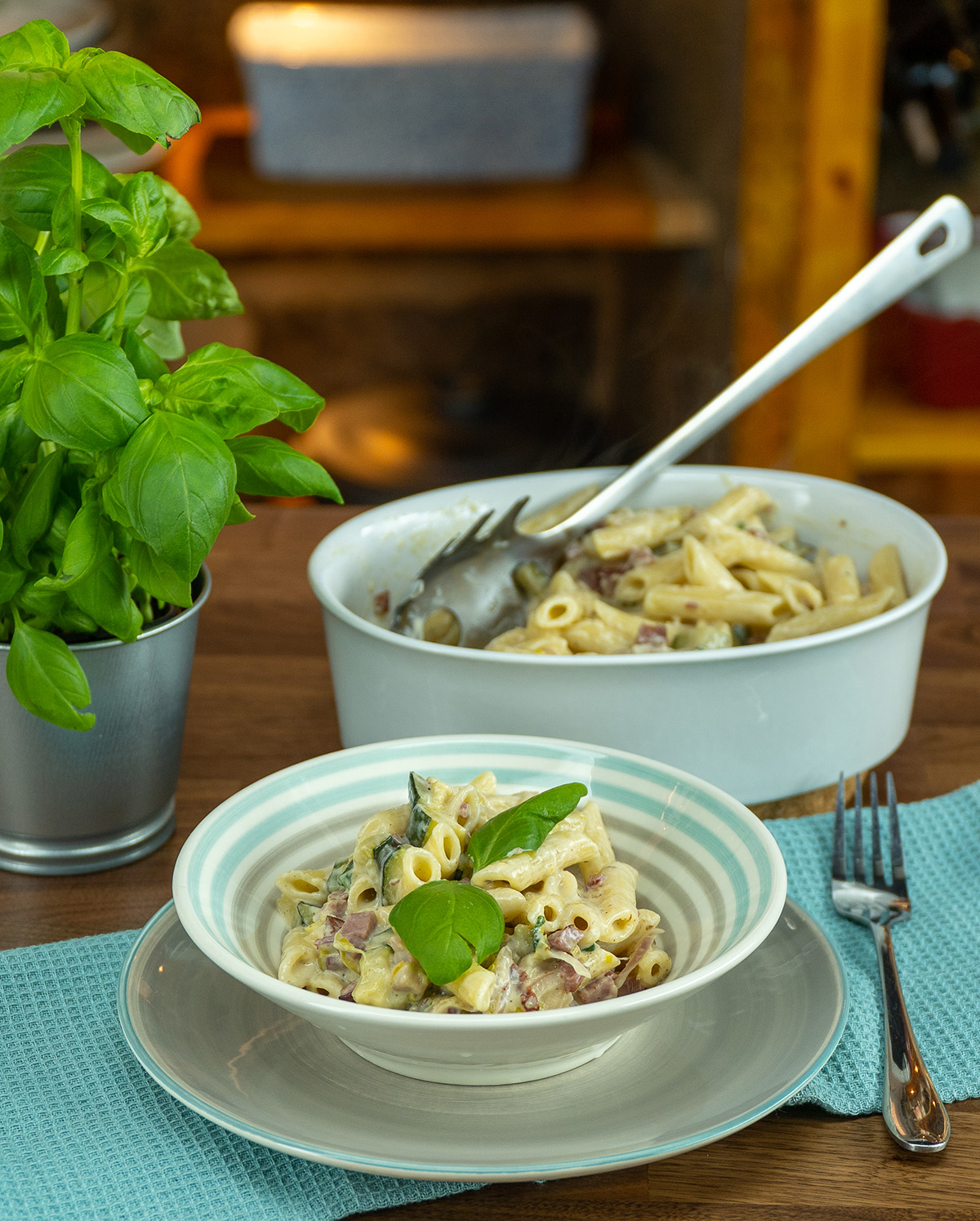Penne with zucchini, bacon and basil served on a plate.
