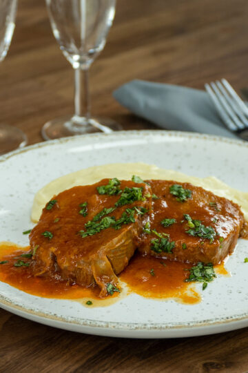 Plate of pressure cooker eye of round roast with mashed potatoes and parsley.