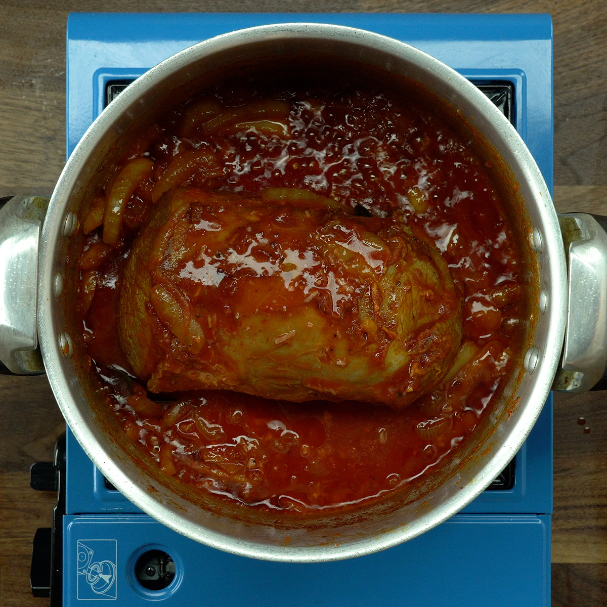Sauce being prepared in the pressure cooker with onion and tomato paste.