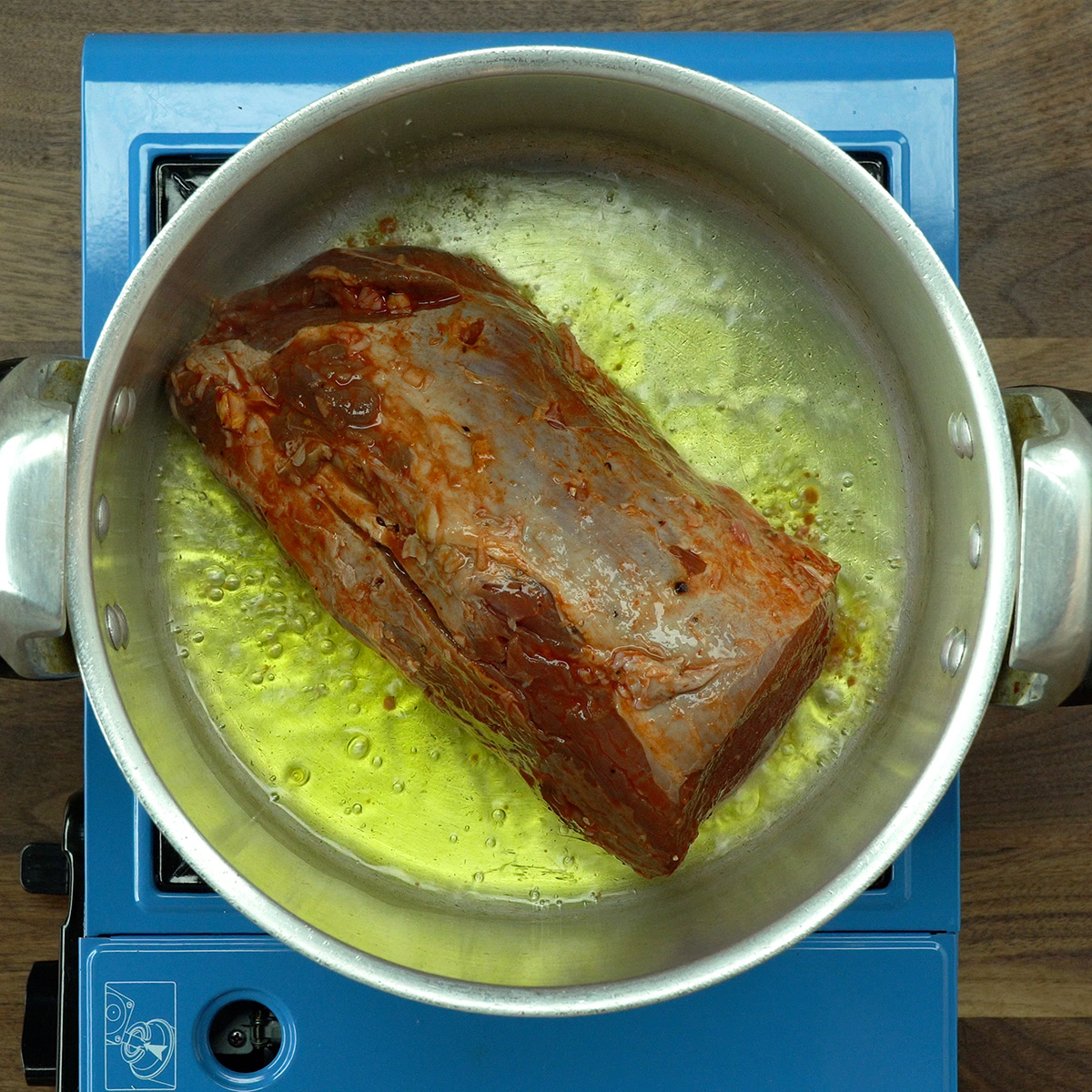 Eye of round roast being seared in the pressure cooker with olive oil.
