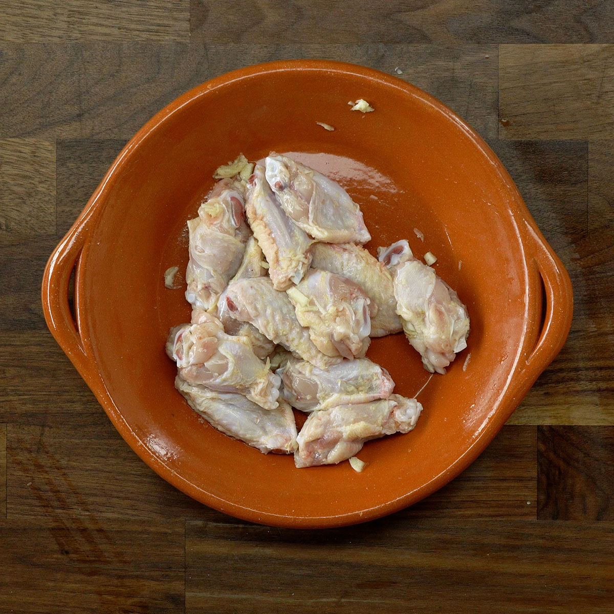 Chicken wings seasoned with garlic and salt in a bowl.