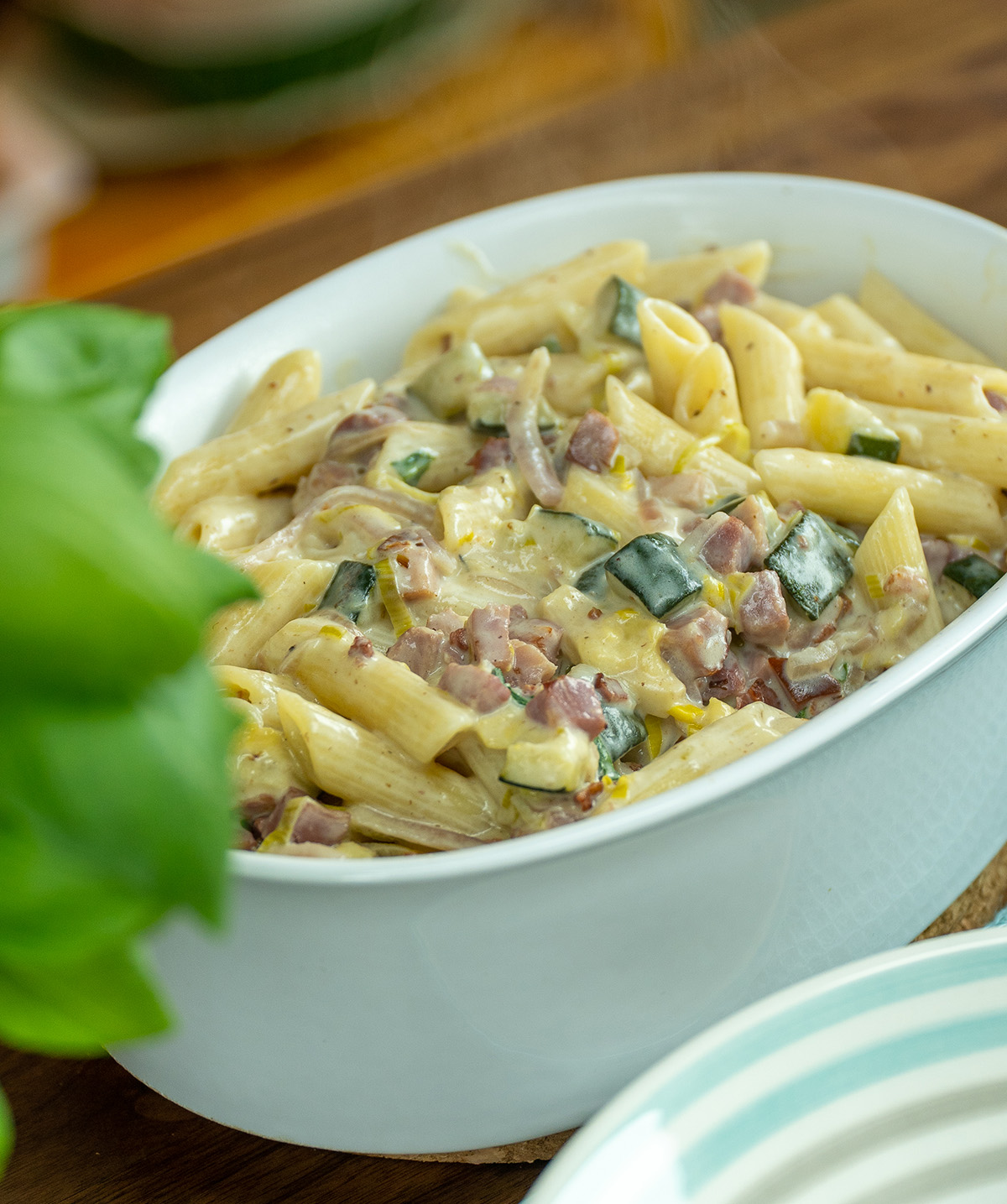 Serving dish with creamy penne, zucchini and bacon.