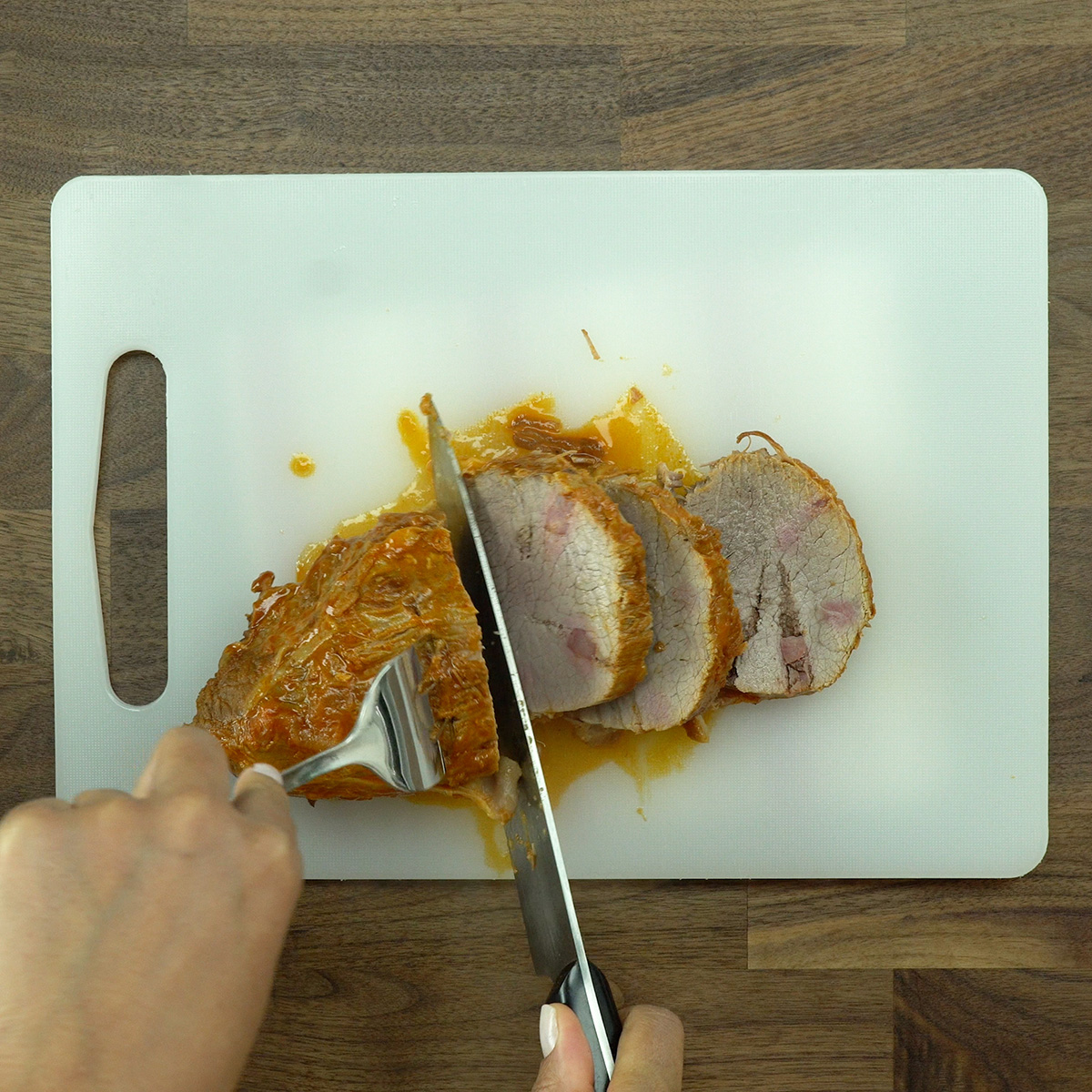 Cooked eye of round roast being sliced into medallions.