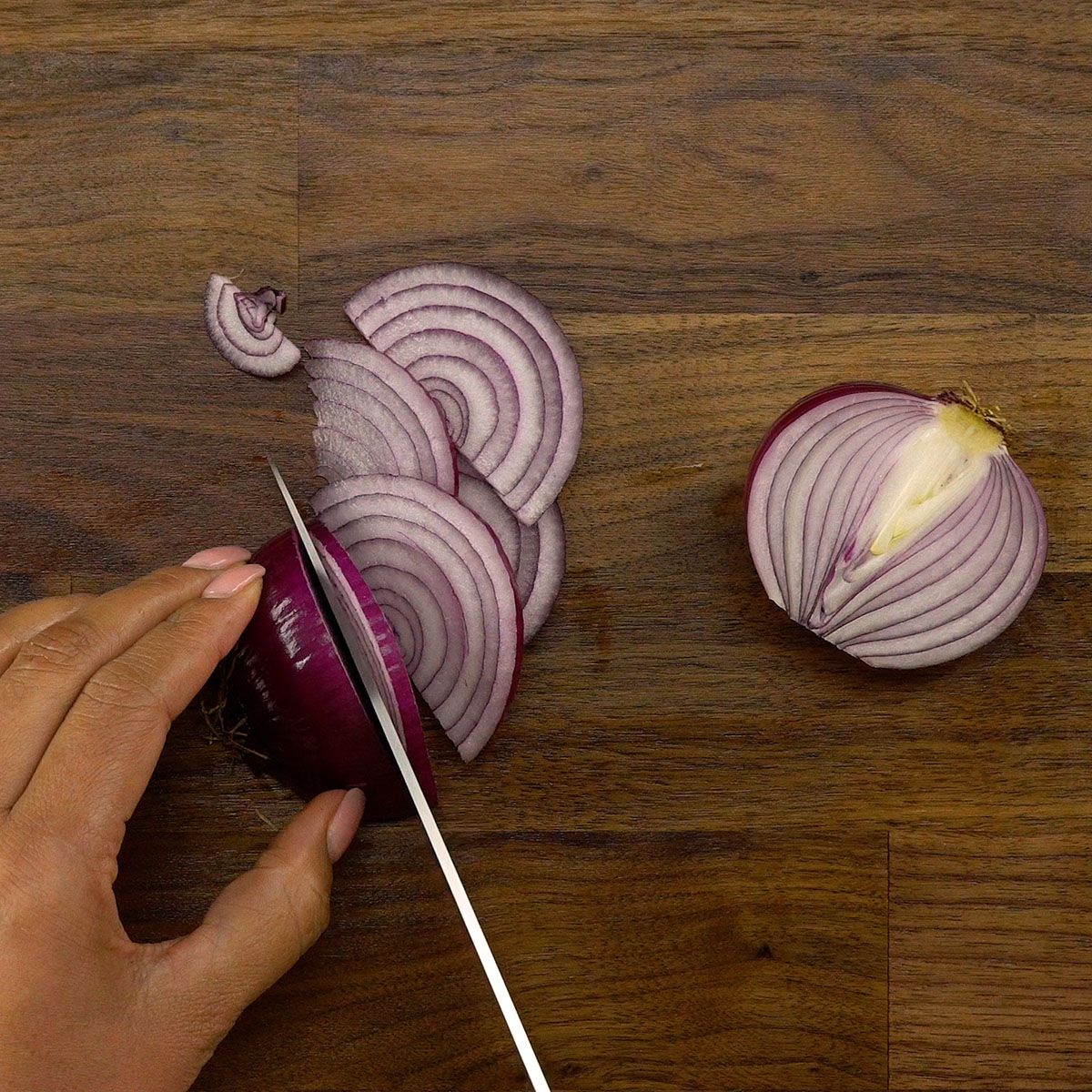 Red onion being sliced thinly.