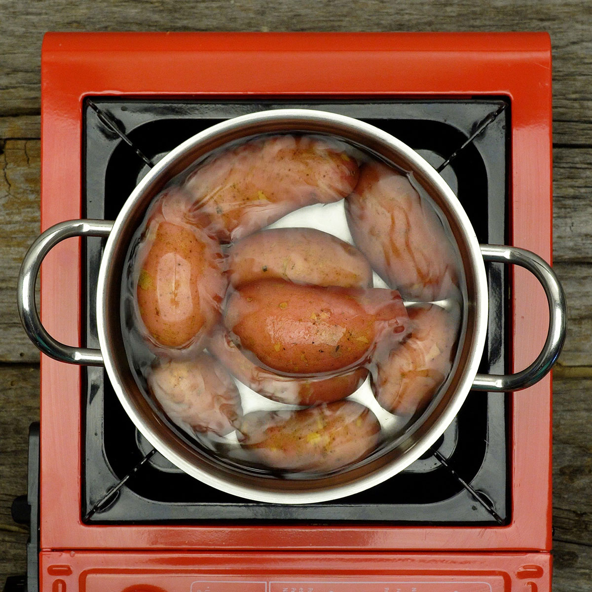 Small whole potatoes boiling in a pot of water on the stove